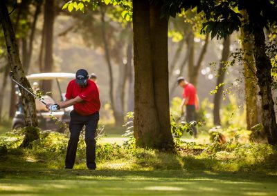 golfer in red plays from trees