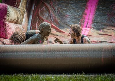 2 women sit in mud